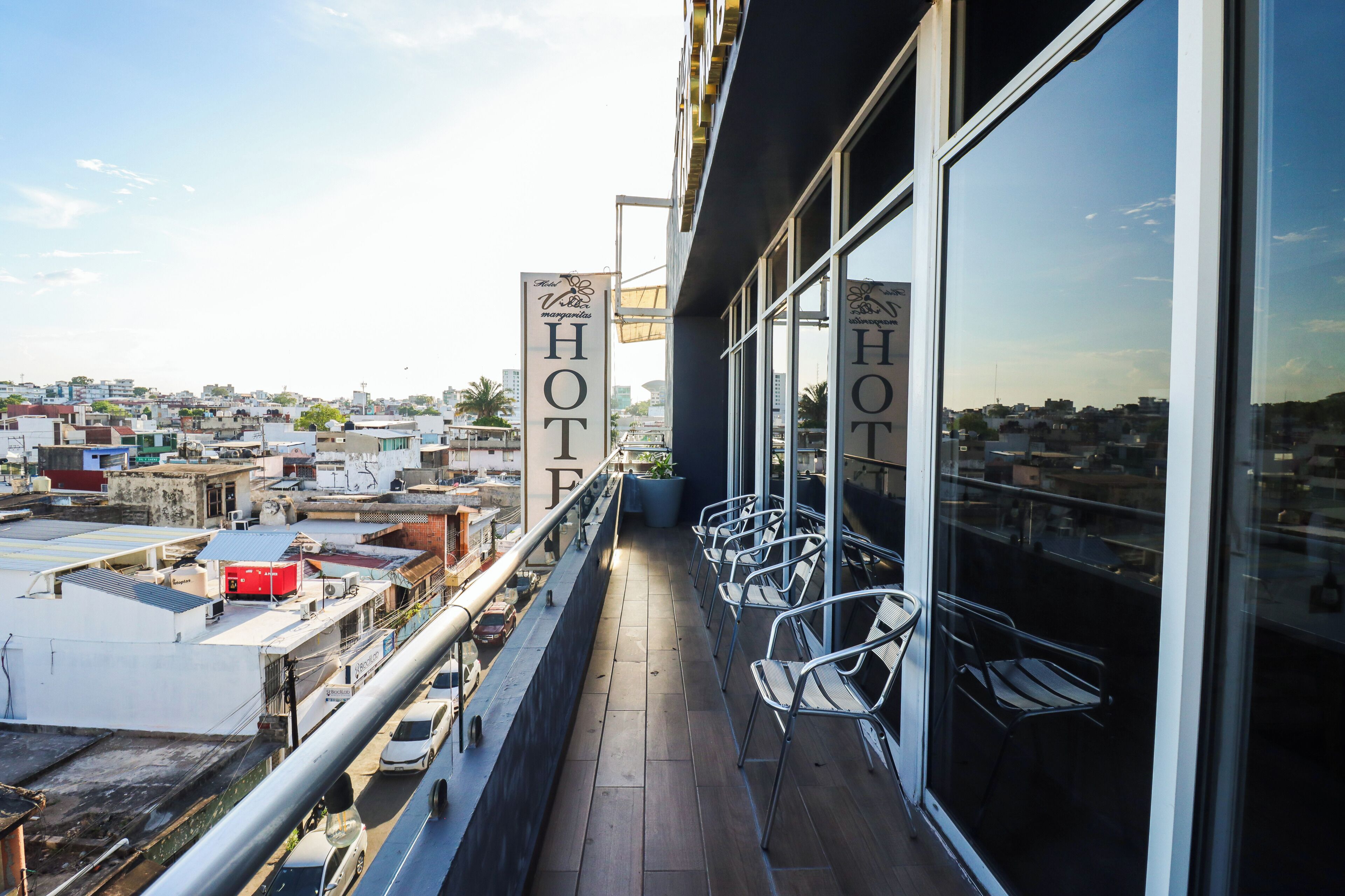 Un balcón de hotel con sillas de metal y vista a la ciudad.