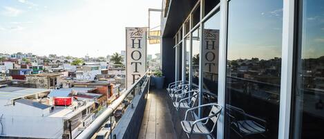 Un balcón de hotel con sillas de metal y vista a la ciudad.