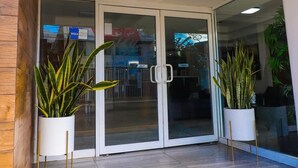 A modern entrance with glass doors, potted plants, and a tiled floor. - Hotel Villa Margaritas (Villahermosa)