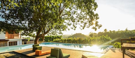 Una piscina al aire libre, sillones reclinables de piscina