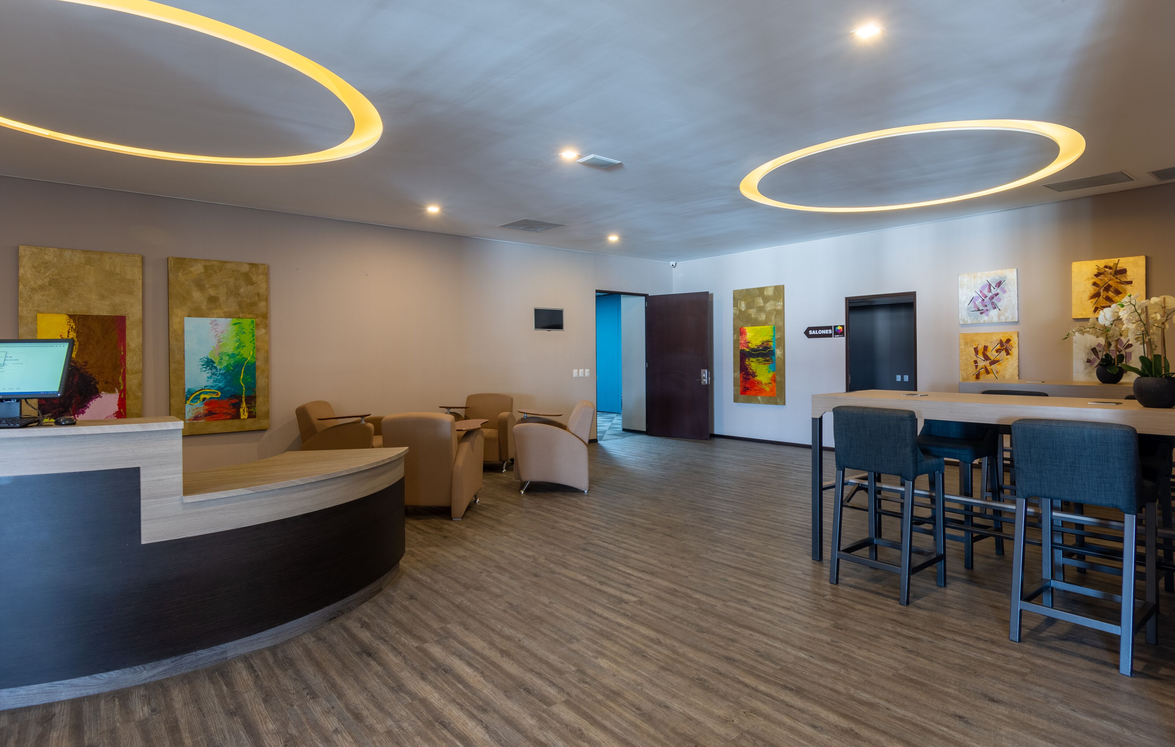 A modern reception area with a curved desk, seating, and artwork on the walls.