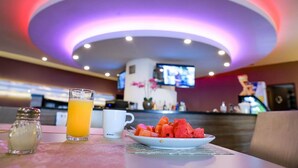 A breakfast table with a plate of watermelon, a glass of orange juice, and a salt shaker. - Hotel Glow Point - Mulza (León)