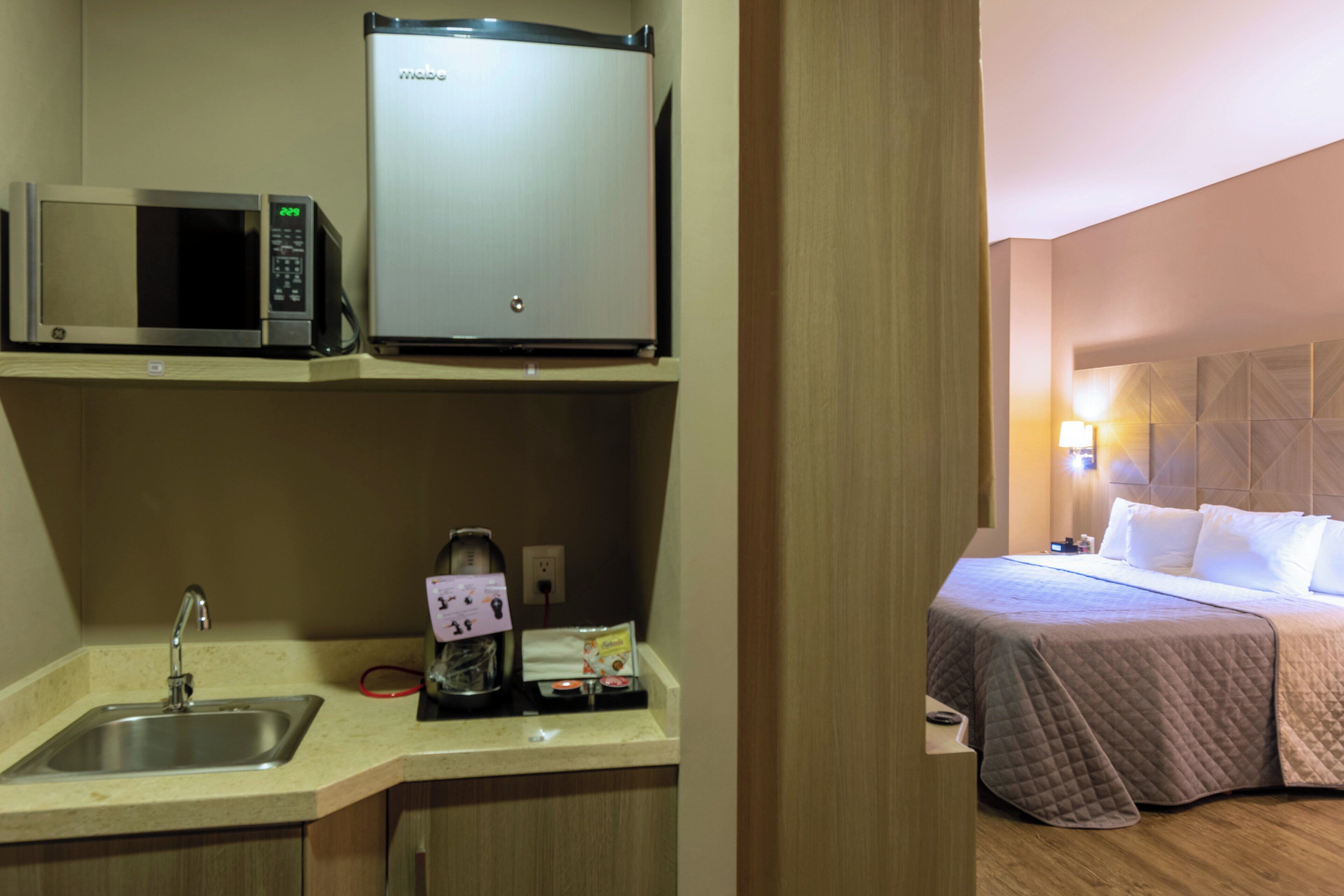 Une chambre d’hôtel équipée d’une kitchenette comprenant un four à micro-ondes, un réfrigérateur et un évier.