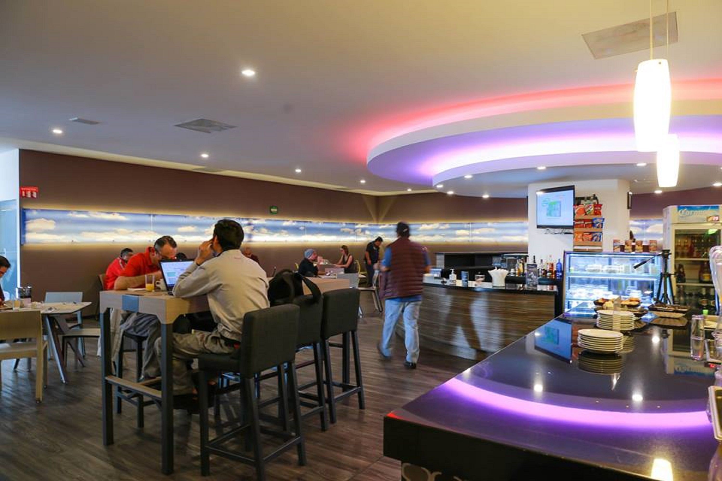 Un restaurante moderno con techo curvo, zona de bar y asientos para los comensales.