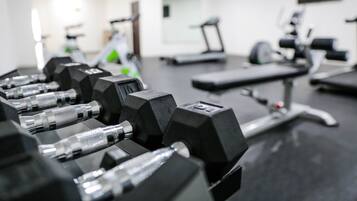 A gym with exercise equipment including dumbbells and a treadmill.