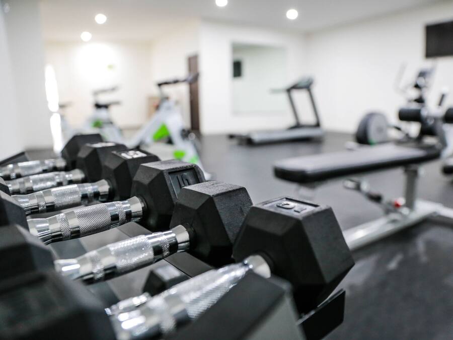 A gym with exercise equipment including dumbbells and a treadmill.