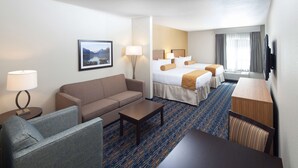 A hotel room with a sofa, a small table, a bed with two pillows, a TV, and a window with curtains. - Red Lion Inn & Suites Polson (Polson)