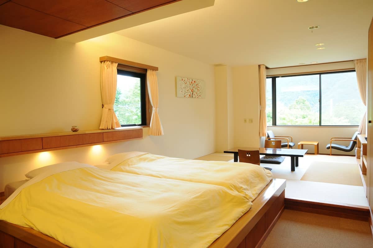 Ein Hotelzimmer mit Bett, Schreibtisch, Stühlen und einem großen Fenster.