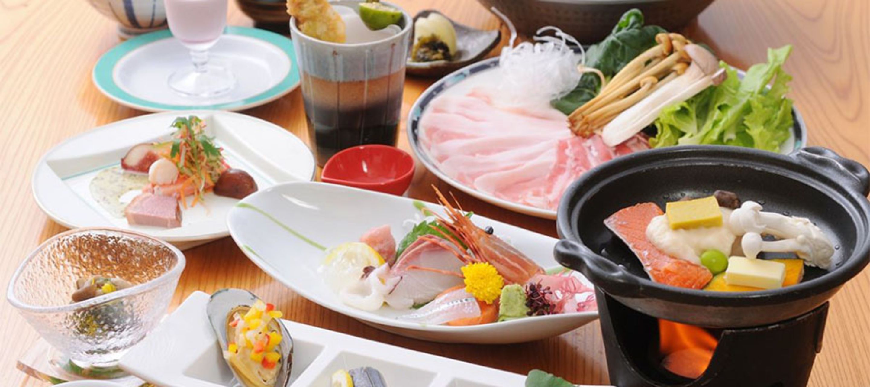 Diversos pratos, incluindo mariscos, legumes e tofu, em travessas, com um pote quente em primeiro plano.