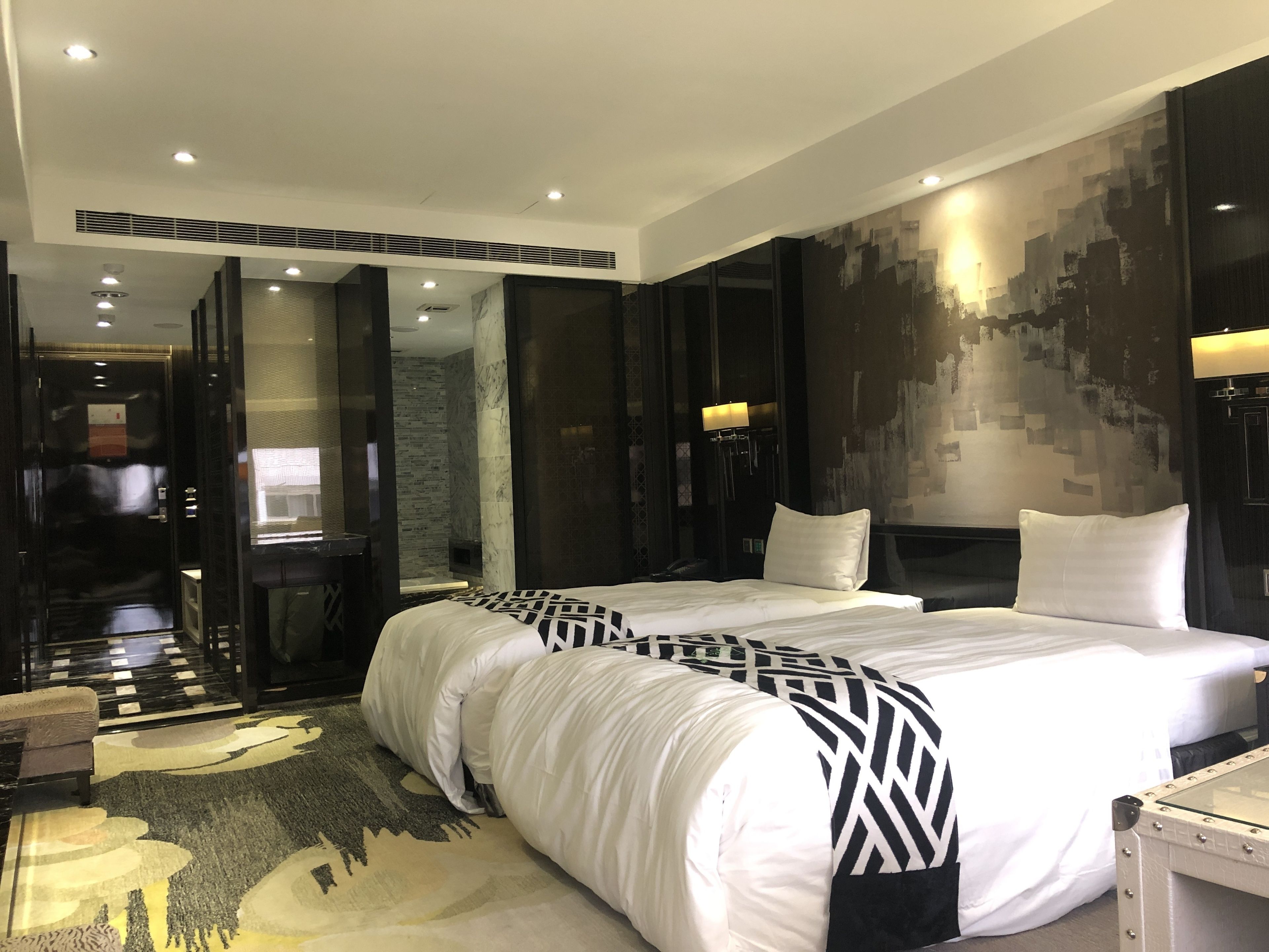 A modern hotel room with a large bed, a desk, and a seating area.