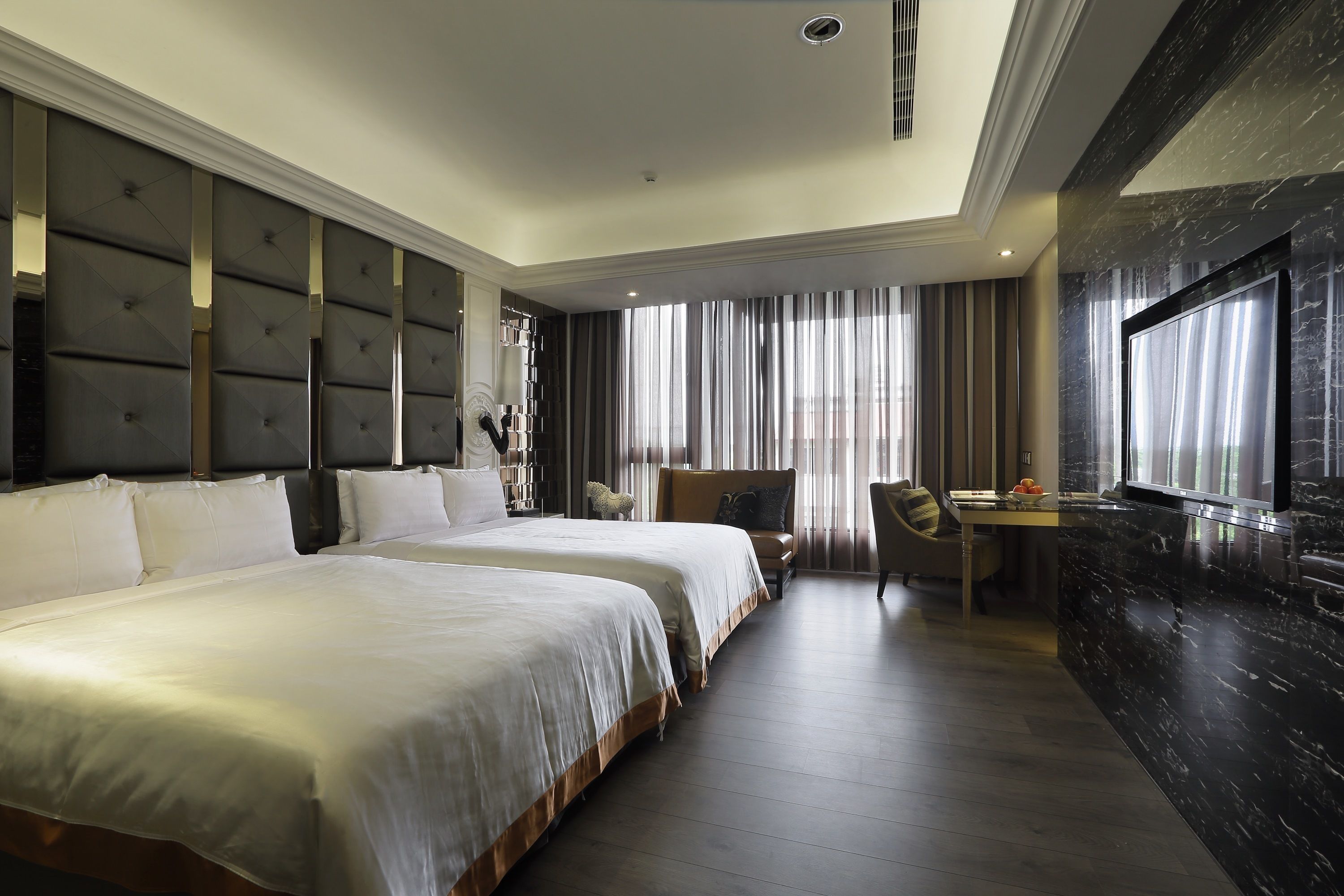 A hotel room with two large beds, a desk, and a TV.