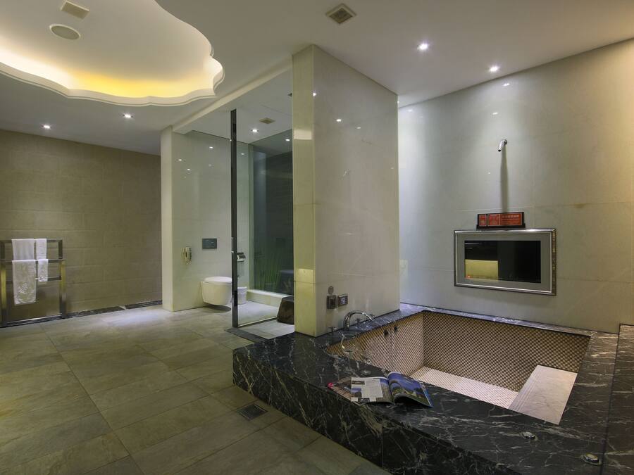 A modern bathroom with a glass shower enclosure, a marble sink, and a built-in towel rack.