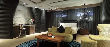 Una habitació d'hotel moderna amb llit, sofà, taula de cafè i escriptori.