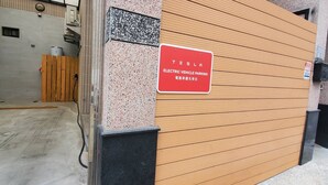 A Tesla electric vehicle parking sign on a building's exterior wall. - Smokey Cat B&B (Taitung)