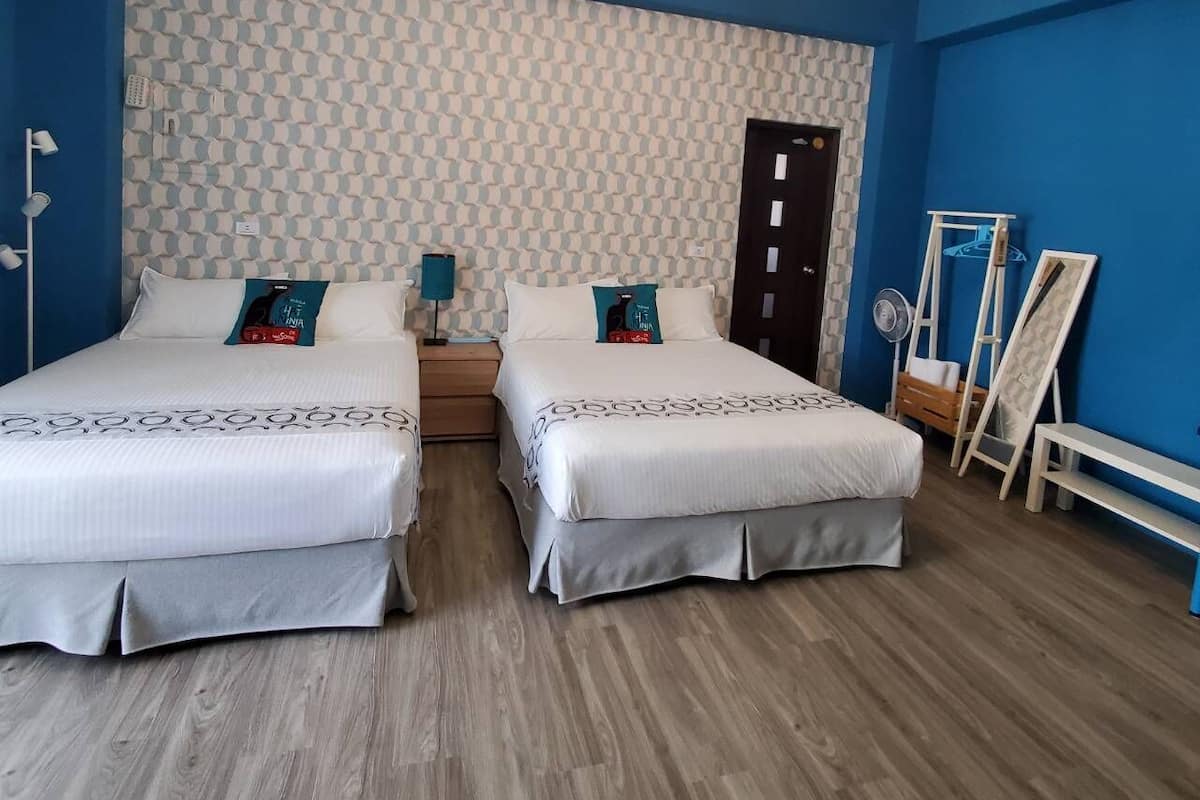 Une chambre double avec deux lits, un lustre, un papier peint à motifs et un miroir.
