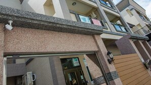 A multi-story residential building with a modern architectural design, featuring a prominent entrance with a glass door and a staircase leading to the upper floors. - Smokey Cat B&B (Taitung)