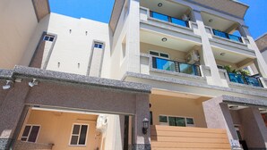 A multi-story building with a garage, balconies, and a clear blue sky. - Smokey Cat B&B (Taitung)