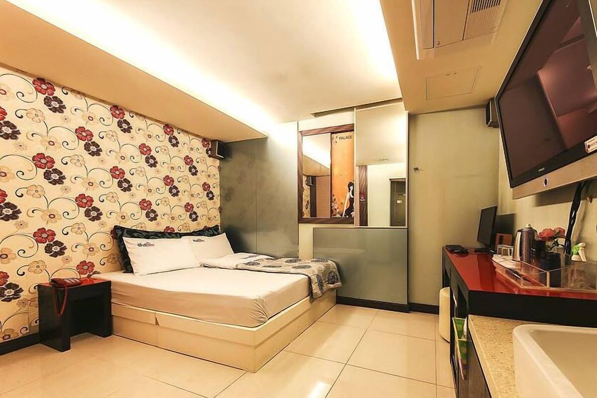 A hotel room with a bed, a TV, a bathroom with a bathtub, and a mirror.