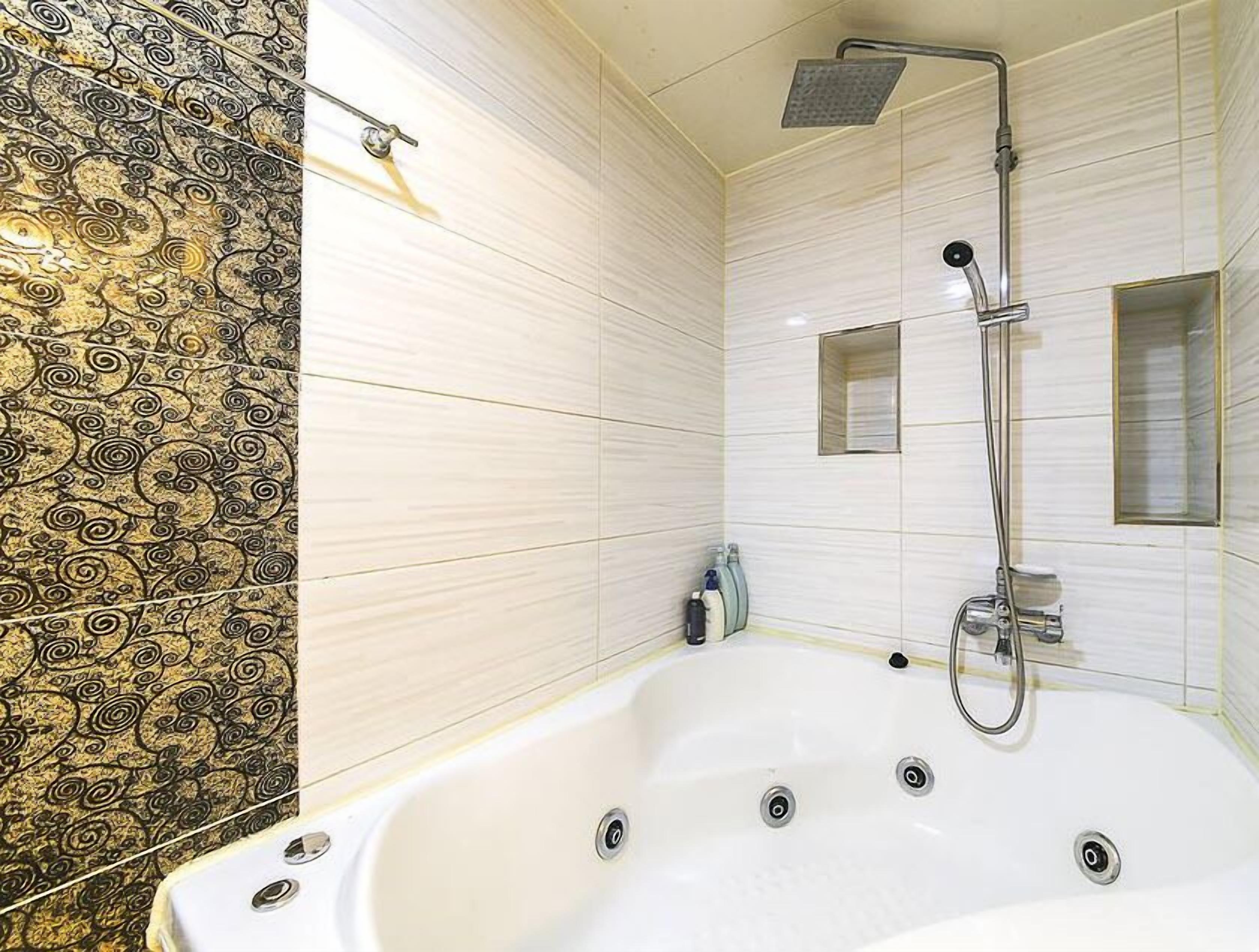 A modern bathroom with a large bathtub, a showerhead, and a small window.