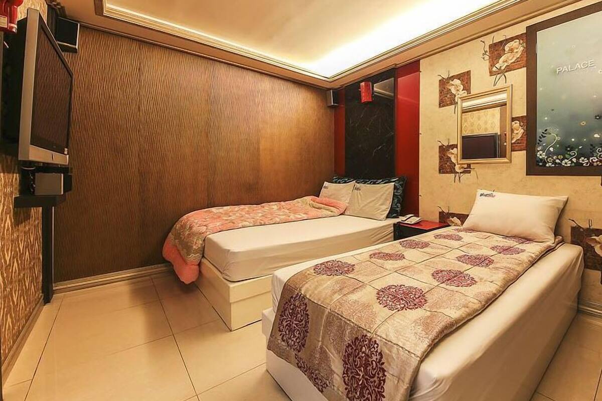 A hotel room with two beds, a TV, and a large window with a view.