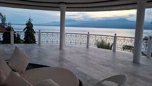 A covered outdoor seating area with a view of a lake and mountains. - Eden Resort (Santander)