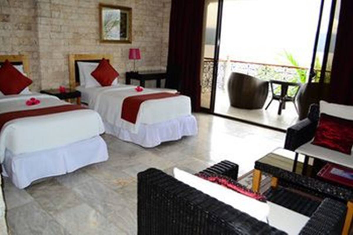 A hotel room with two beds, a balcony, and a seating area.