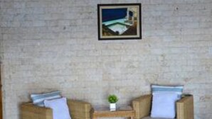 A room with two wicker sofas, a small wooden table, and a framed picture on the wall. - Eden Resort (Santander)