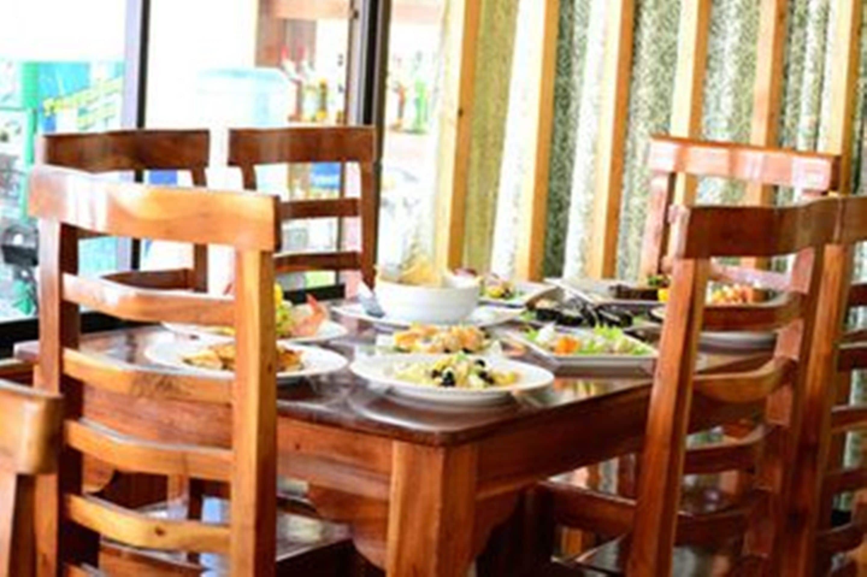 A wooden dining table with multiple chairs, surrounded by various dishes and a white bowl.