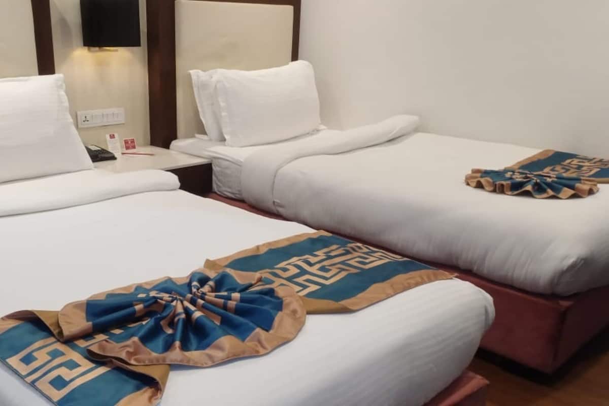 Two single beds with white linens and a decorative blue and beige throw blanket on the left bed.