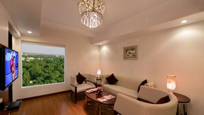 A modern living room with a television, a sofa, two armchairs, a coffee table, and a chandelier. - Lords Inn Jodhpur (Jodhpur)