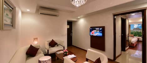 Una sala de estar moderna con candelabro, asientos cómodos, televisor de pantalla plana y vistas al exterior.