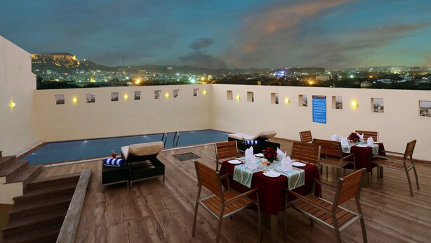 A rooftop terrace with a pool, dining area, and city views at dusk. - Lords Inn Jodhpur (Jodhpur)