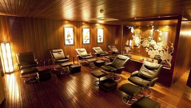 A room with wooden paneling, multiple massage chairs, and framed artwork on the walls. - Grand Medallion Hotel (Kuching)