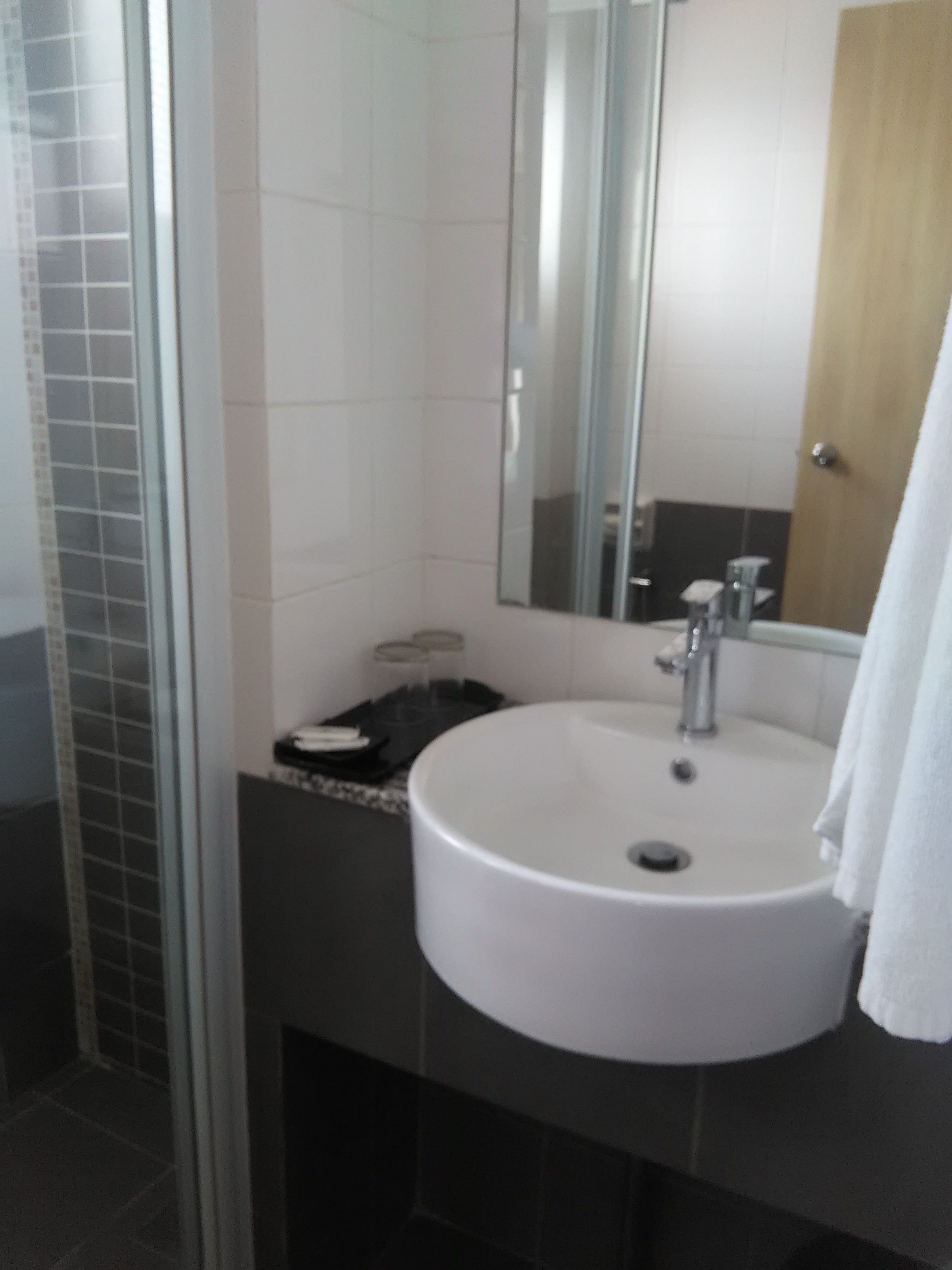 A bathroom with a white sink, a mirror, and a shower area.