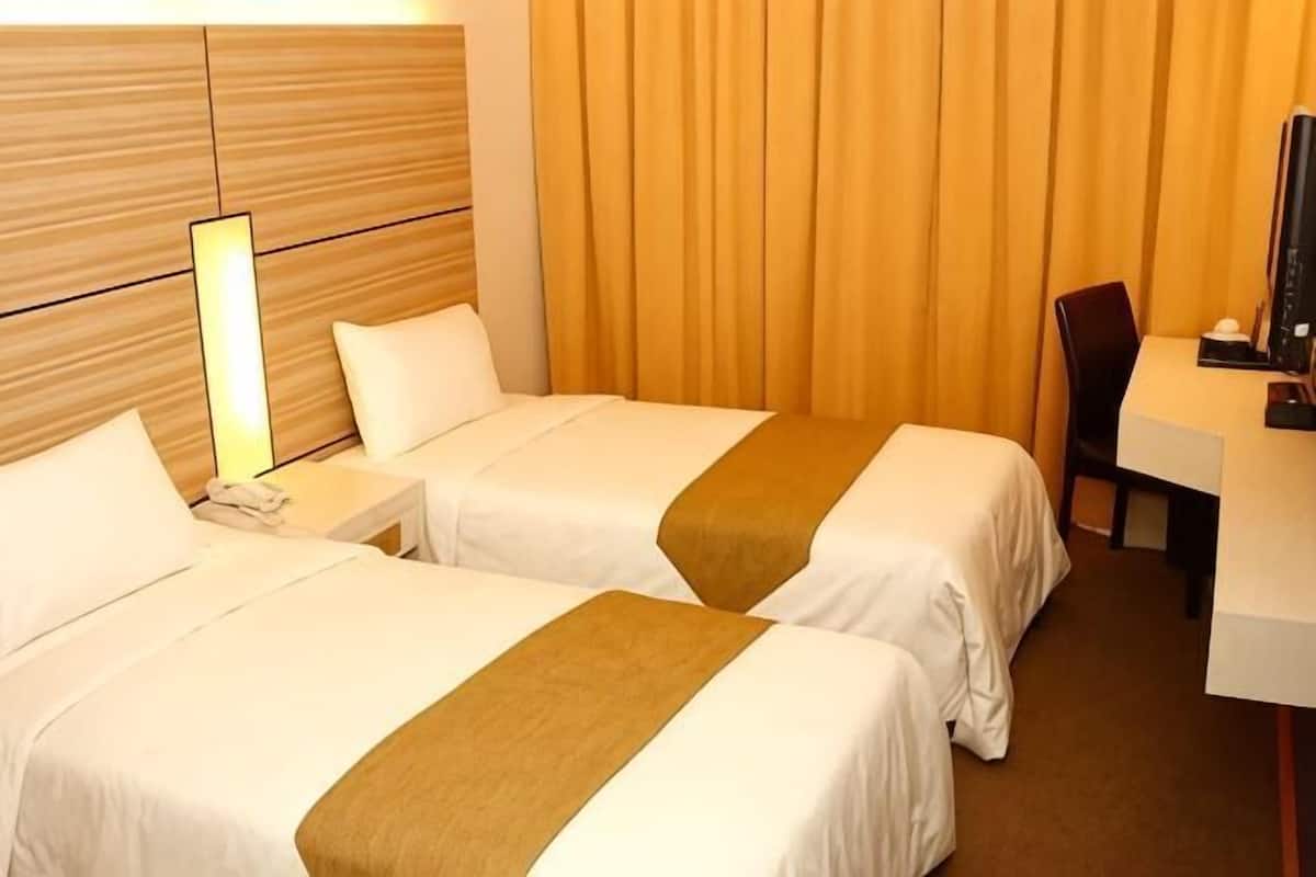 A hotel room with two beds, a desk, a chair, and a TV.