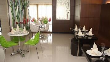A dining area with modern furniture, including green chairs and a round table with white plates and napkins.