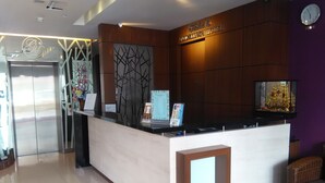 A hotel reception desk with a modern design, a clock, and a sign indicating the hotel name. - Grand Medallion Hotel (Kuching)