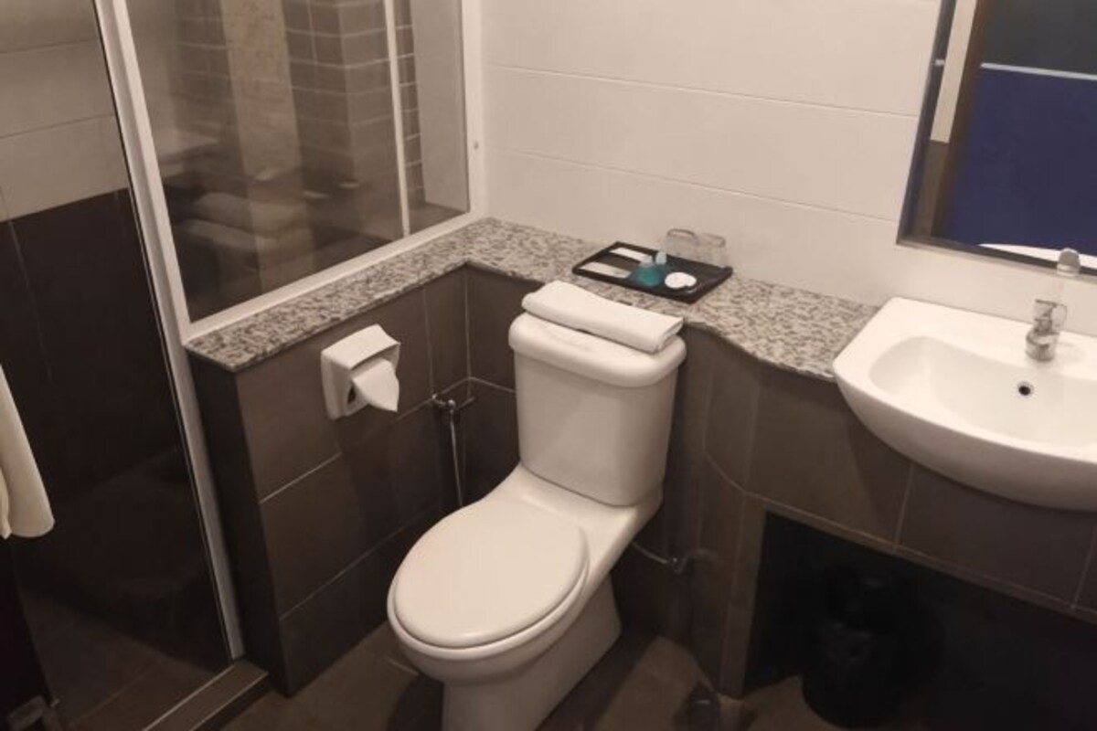 A bathroom with a toilet, sink, and shower area.