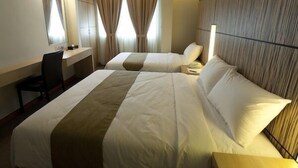 A hotel room with two beds, a desk, and a chair. - Grand Medallion Hotel (Kuching)