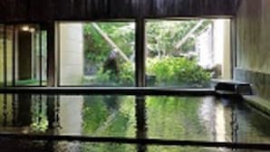 A room with a large window, a wooden ceiling, and a view of greenery outside.