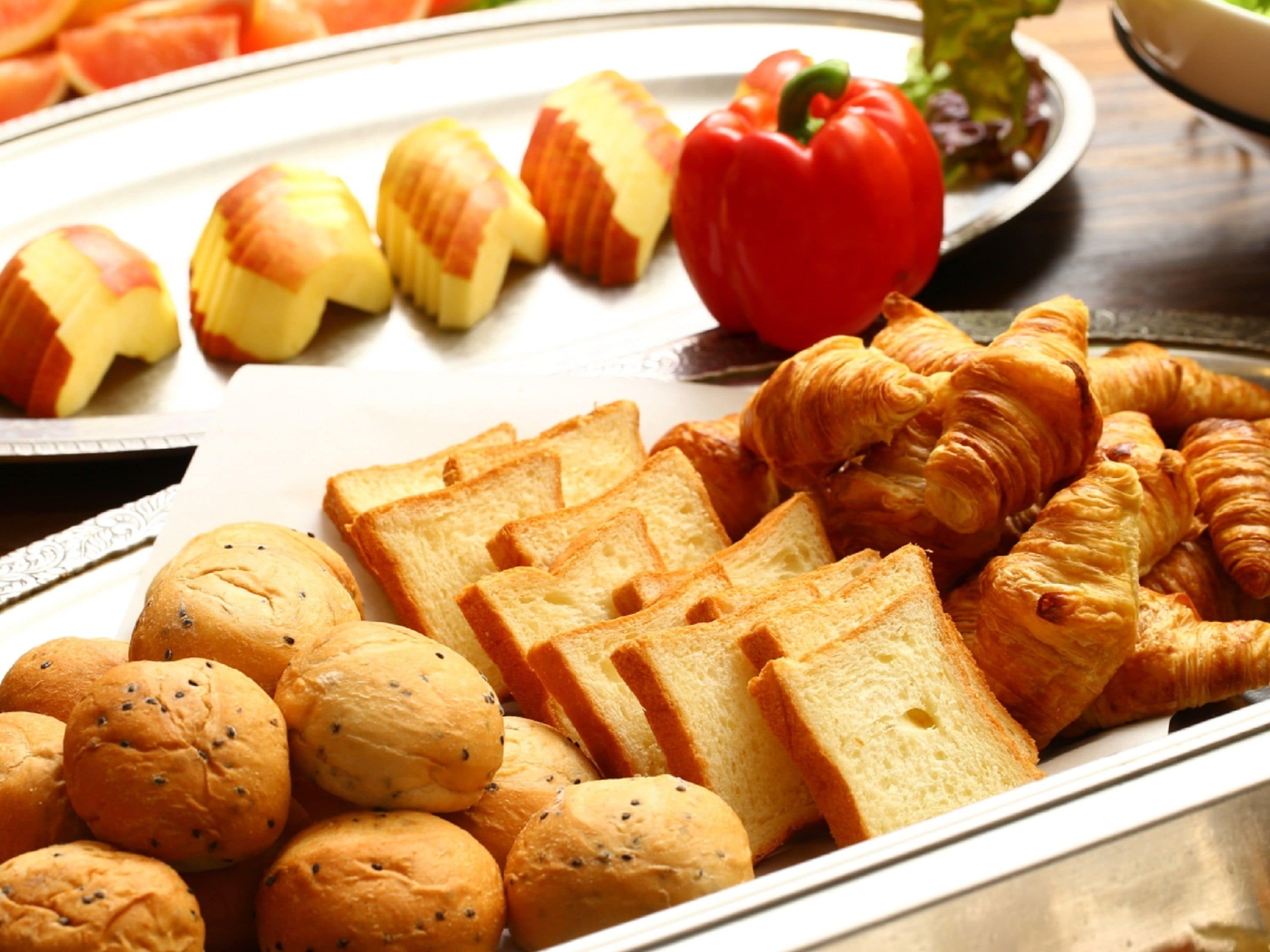 A tray of assorted baked goods including bread, croissants, and rolls.
