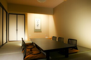 Una habitación tradicional japonesa con suelo de tatami, una mesa baja y sillas negras.