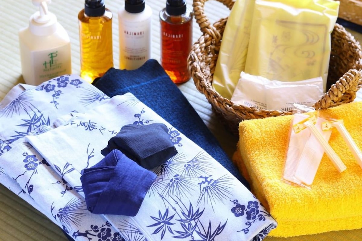 A neatly arranged bathroom with towels, bath products, and a basket of toiletries.