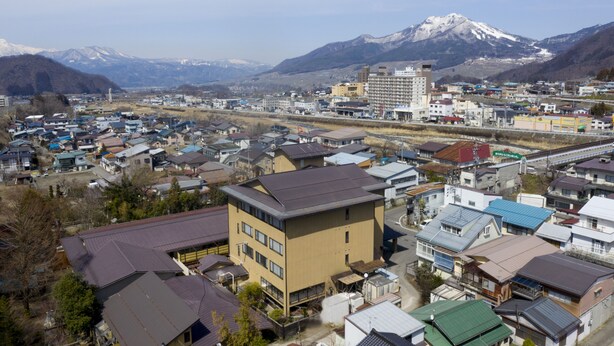 A town with a mix of residential and commercial buildings, a prominent hotel with a modern design, and a mountain in the background.