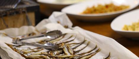 Una mesa de buffet con diversos platos, incluyendo una bandeja de pescado frito.