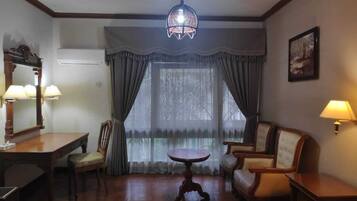 A hotel room with a bed, a round table, two chairs, a desk, and a lamp.