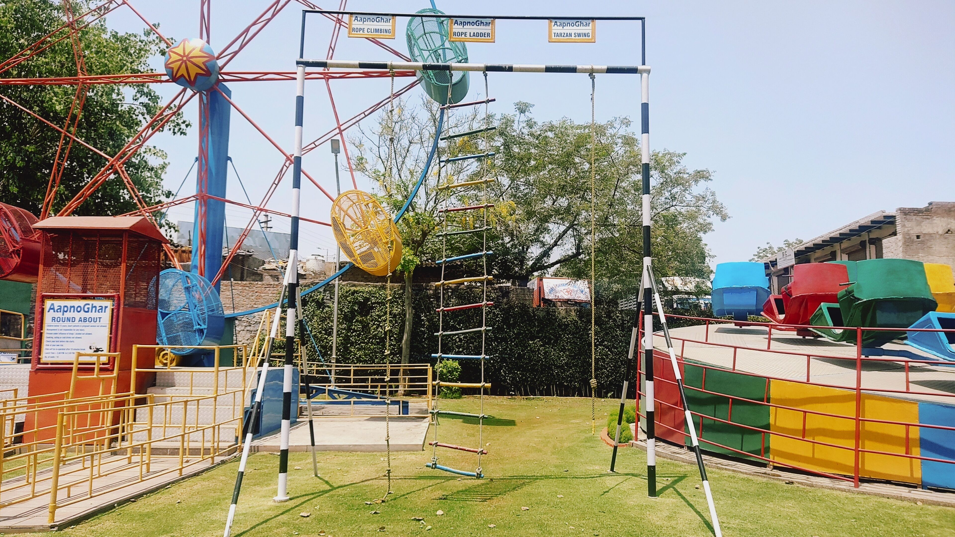 Ein Spielplatz mit Kletterseil, Schaukel und Riesenrad.
