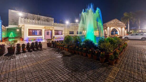 A fountain, potted plants, a building with a sign, and a car. - Aapno Ghar Resort (Gurugram)