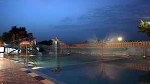 A swimming pool with a water slide and a bridge. - Aapno Ghar Resort (Gurugram)
