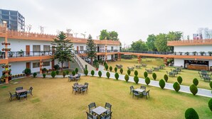 A courtyard with outdoor seating, a staircase, and a building with balconies. - Aapno Ghar Resort (Gurugram)